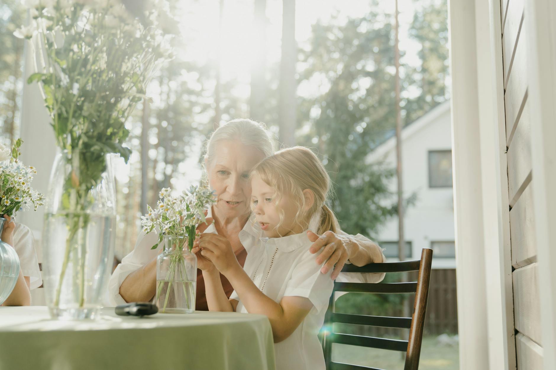 grandmother and granddaughter sitting at a table arranging flowers