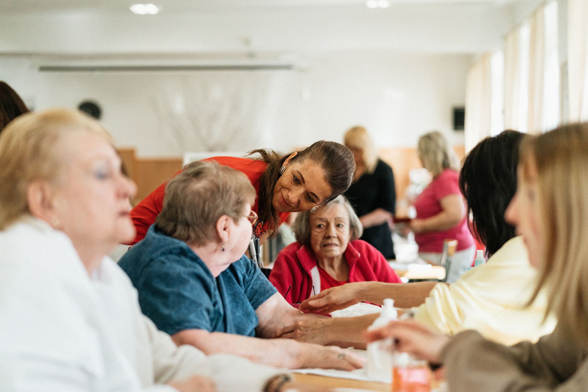 a caregiver talking to a group of seniors sitting at a table