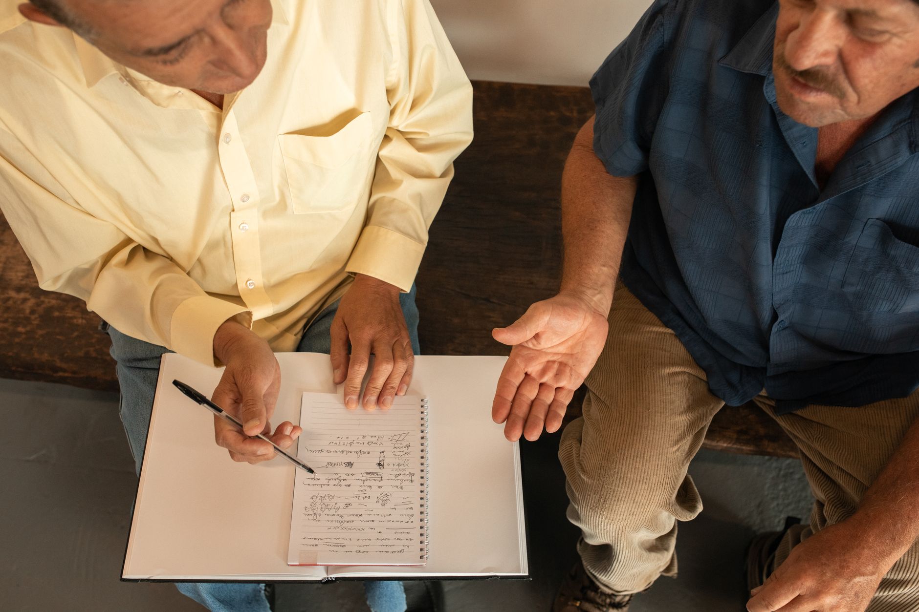 man in yellow long sleeve shirt sitting beside a man in blue button up shirt